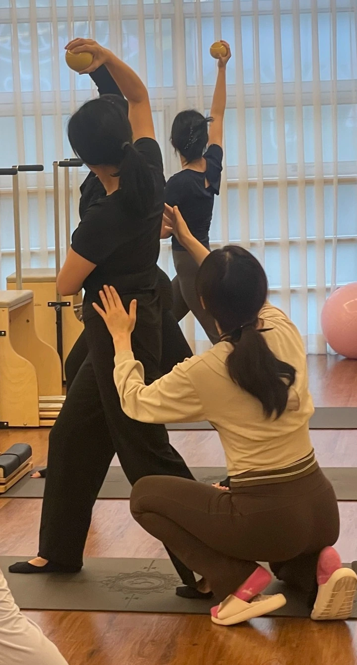 그룹수업 중 강사가 회원의 몸통과 골반 움직임을 확인하는 장면
