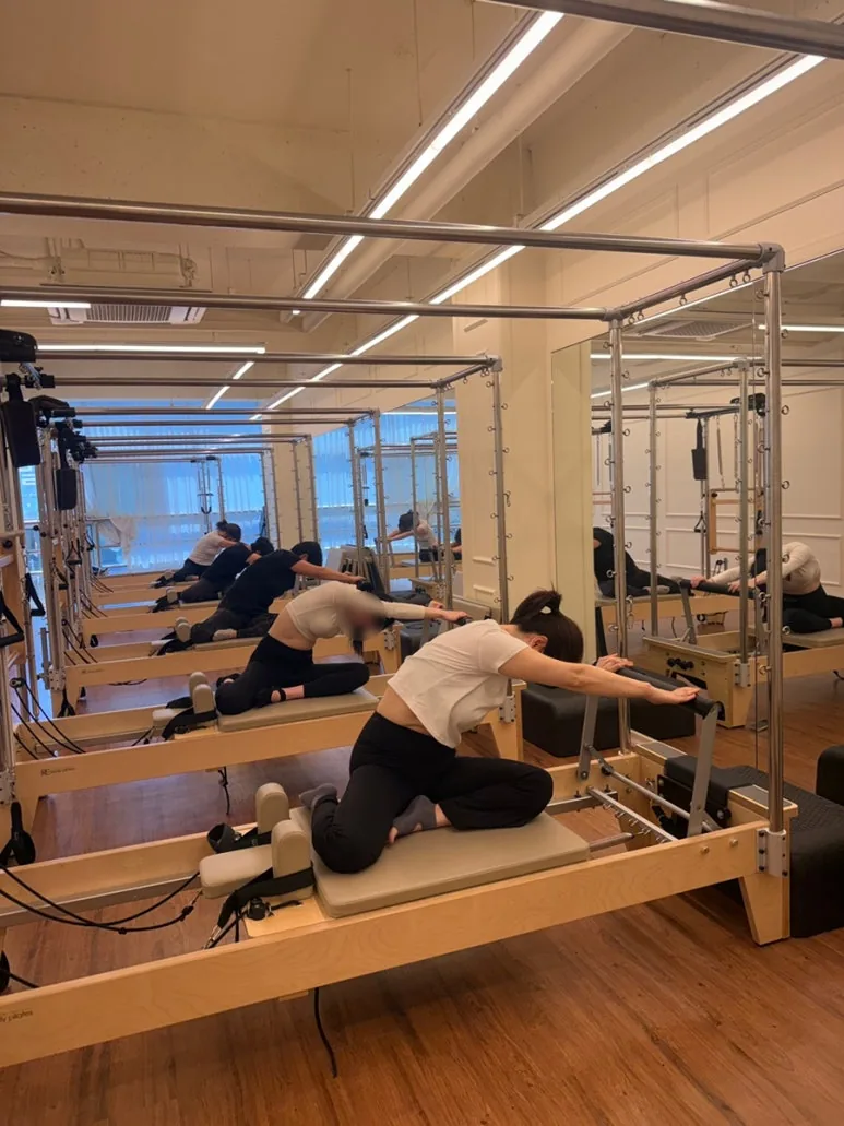 여러 회원이 캐딜락 기구에서 함께 스트레칭 동작을 진행하는 그룹수업