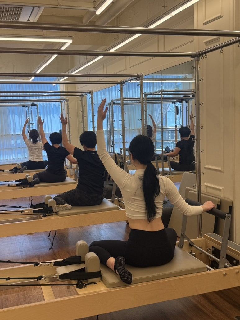 회원들이 리포머 기구에서 함께 팔 동작을 진행하는 그룹수업
