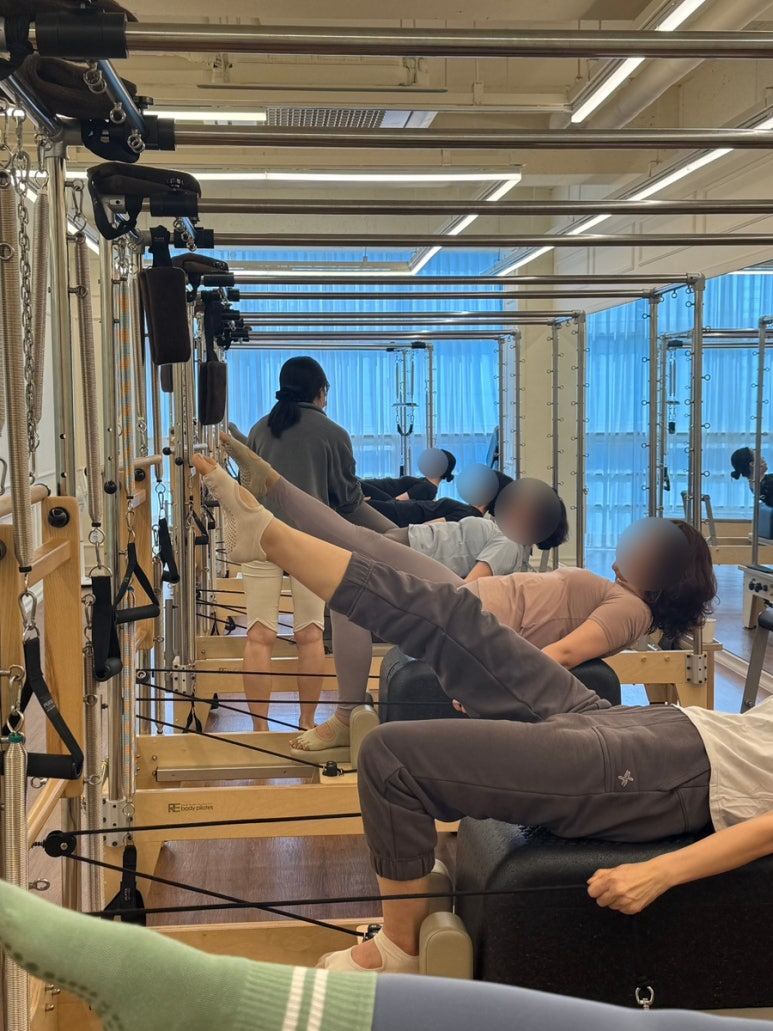 회원들이 캐딜락 기구에 누워 다리 동작을 진행하는 그룹수업
